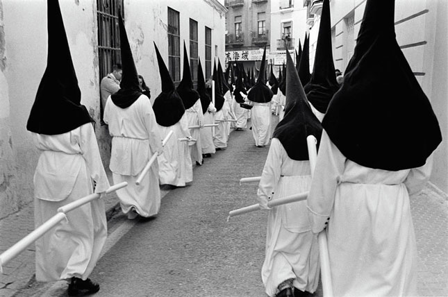 AZ ÖRÖKIFJÚ SEMANA SANTA Átbaktatni csúcsos csuklyádban a kedvetekért leállított gyorsforgalmi úton, a kínai vendéglő előtt, miközben a fiad a mobiltelefonjára csinál rólatok képet, hogy elküldje azonnal a kórházban fekvő Nagyinak: Semana Santa… Fotó: Molnár Zoltán